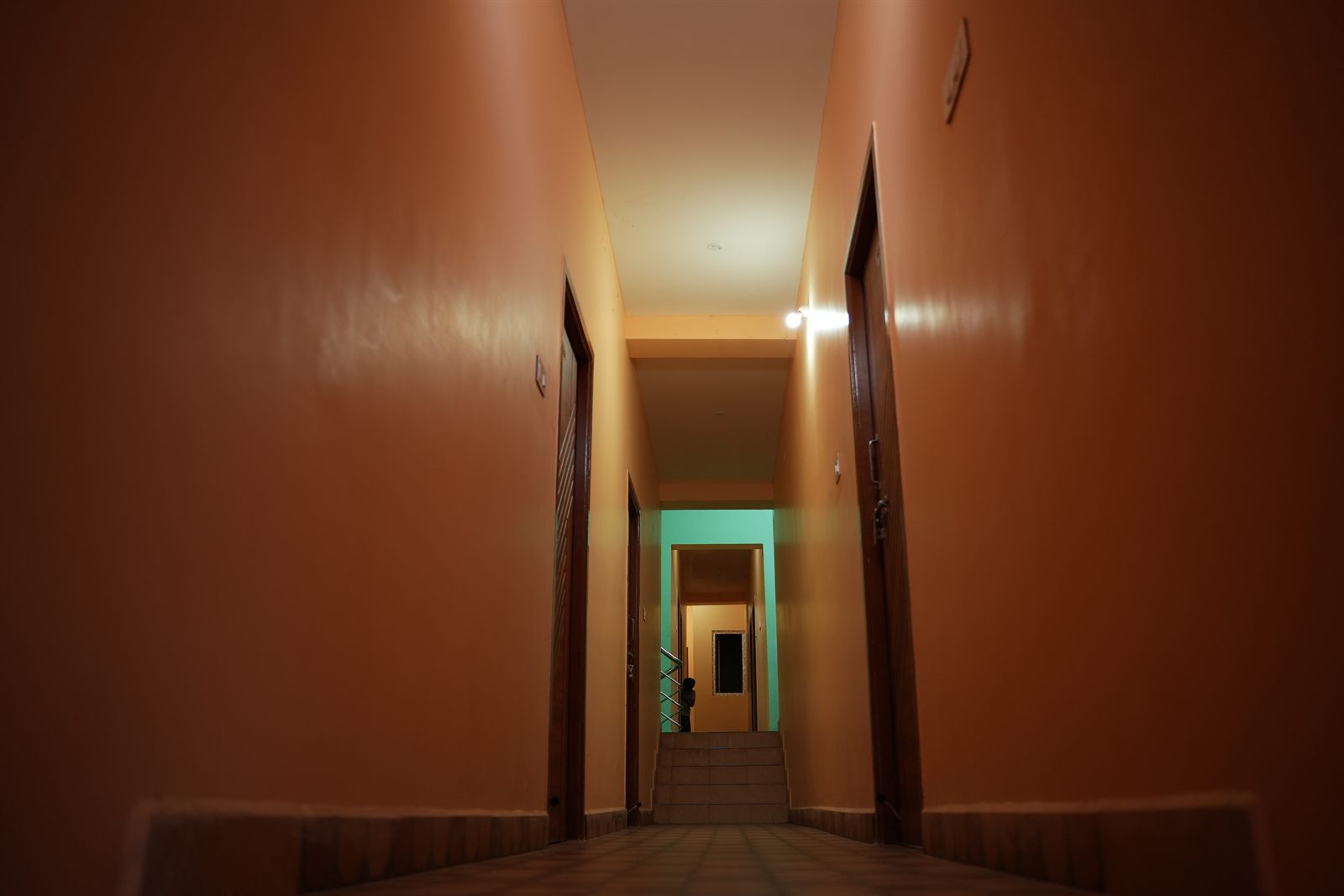 Upper-floor corridor with orange walls and wooden room doors