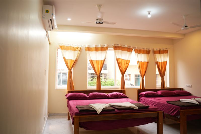 Large family room with multiple beds and three curtained windows