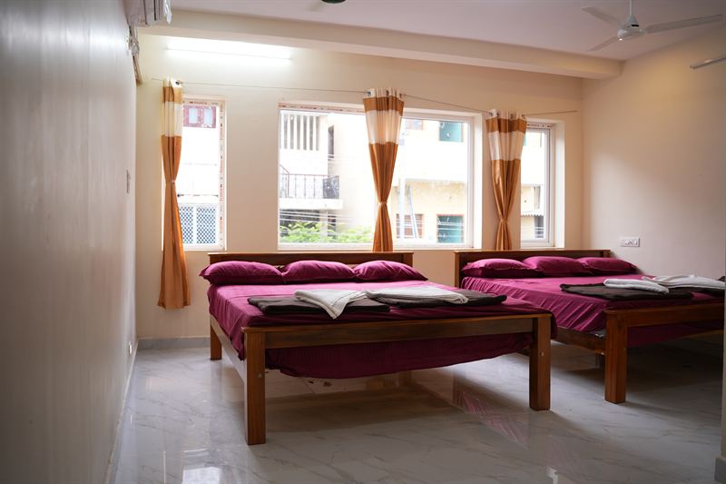 Family room with two beds and orange curtained windows in daylight
